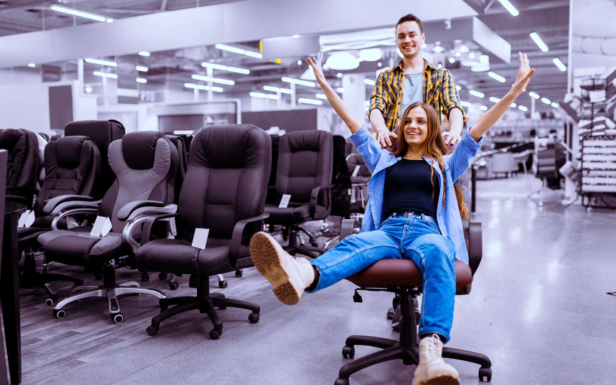 Couple rides on office chair in furniture store
